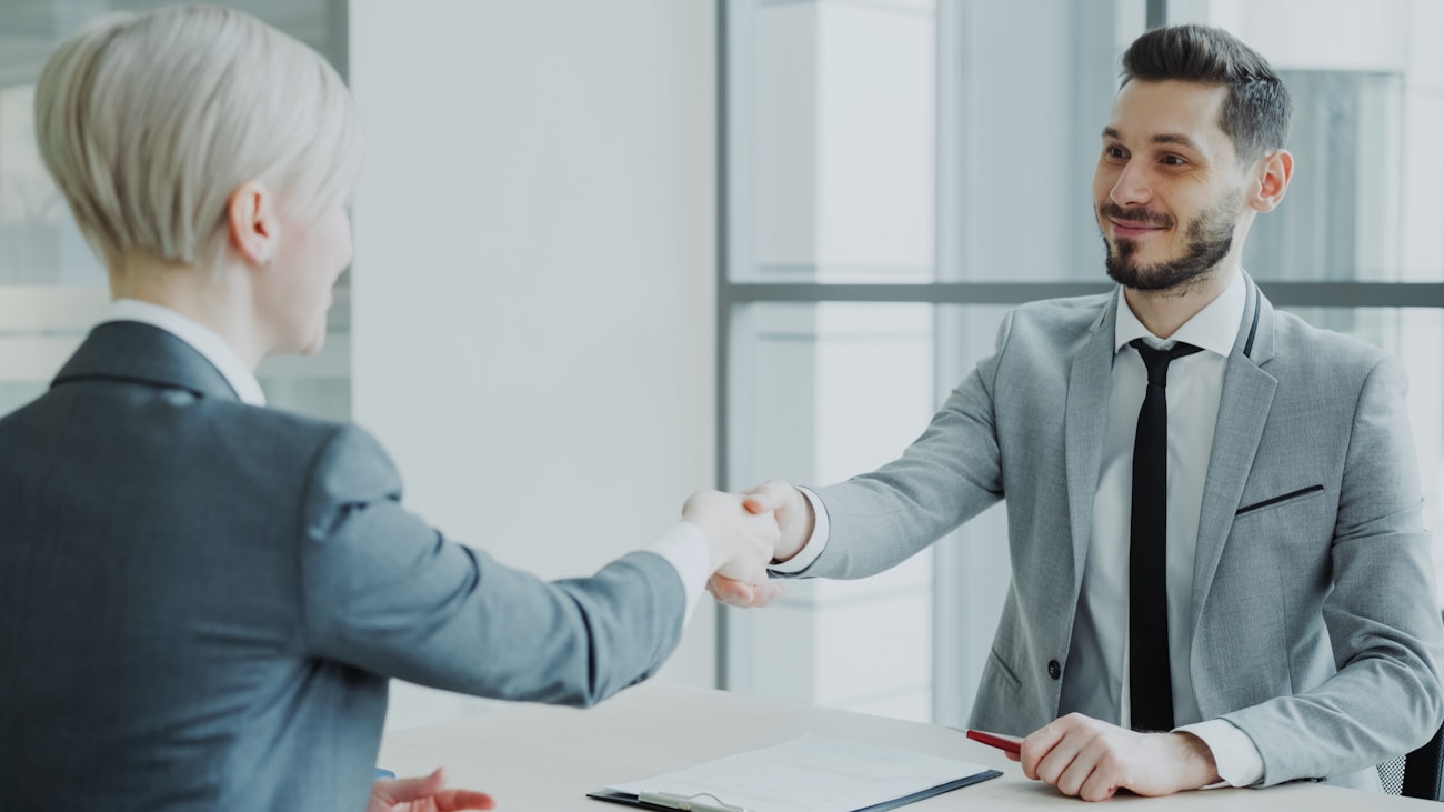 Two professionals shaking hands across a desk