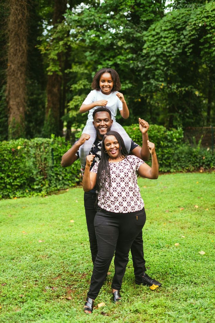 A joyful family with parents and a child on father's shoulders outdoors
