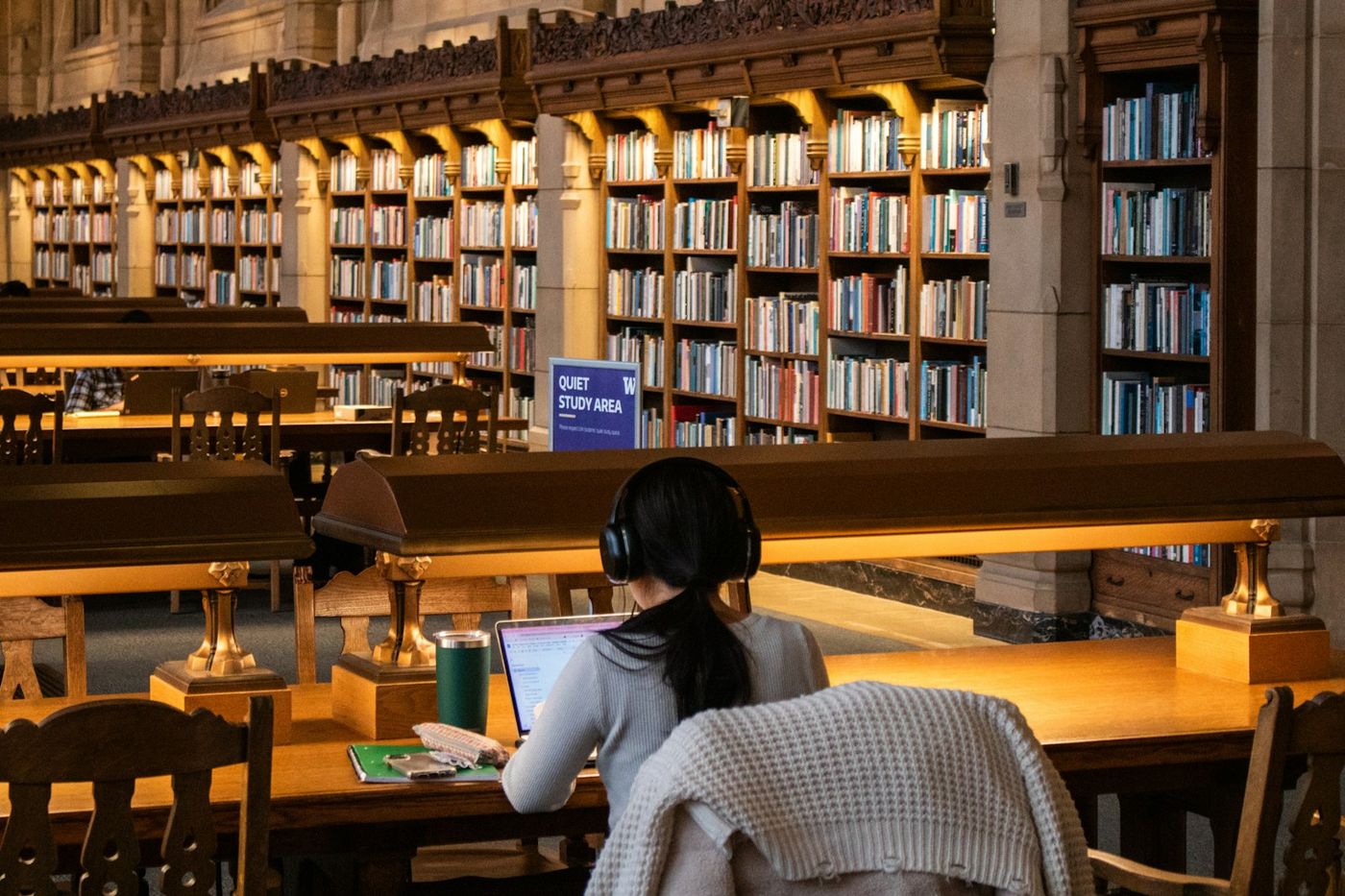 A student studying with a laptop in an ornate Canadian university library